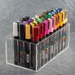 Clear acrylic divided box art marker/pen caddy filled with colorful Uni Posca pens.