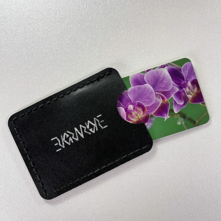Hand-stitched black cactus leather card case with an engraved and painted silver Evermore ambigram logo, business cards with an image of a string of orchids protrude.