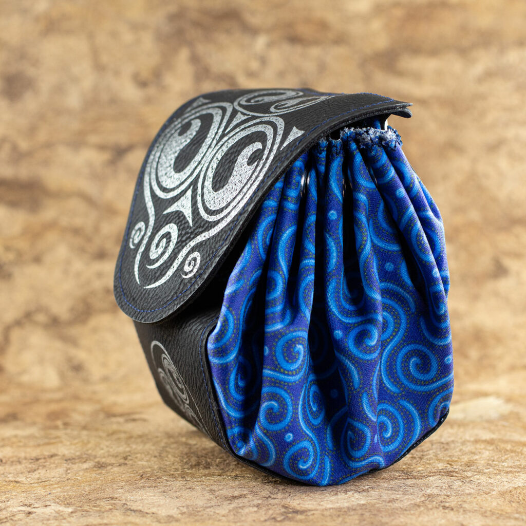 A small fantasy/Medieval belt pouch. The main body is cotton fabric printed with interlocking Celtic spirals in various shades of blue. The front, bottom, back and flap are black faux/vegan leather. The flap is decorated with silver spirals and, there is a sliver spiral triskelion on the front below the flap.