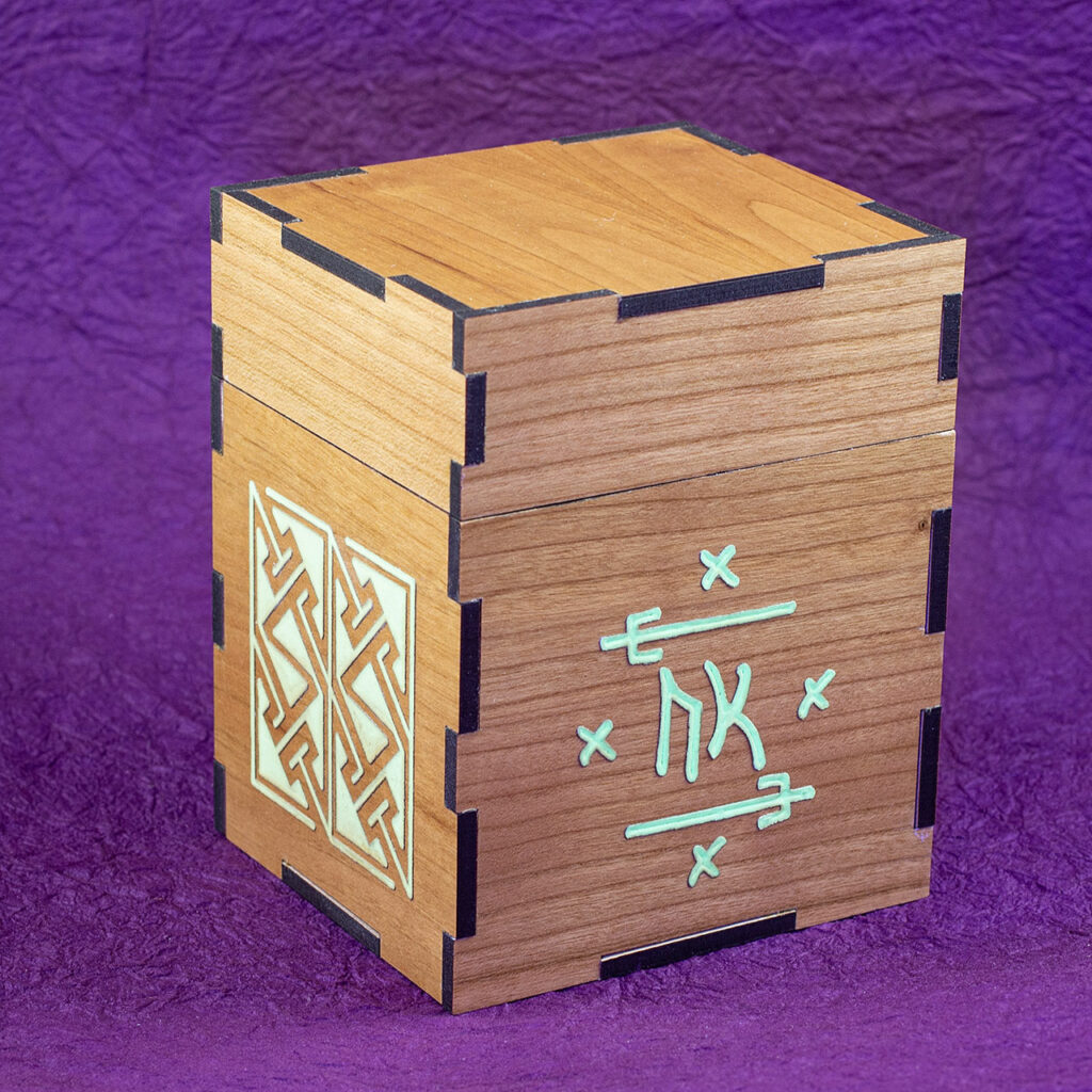 Wood sleeved "commander" deck box for M:tG and similar games with glowing engraved designs: an embellished Futhark rune on the front and, a Celtic key pattern panel on the left side.