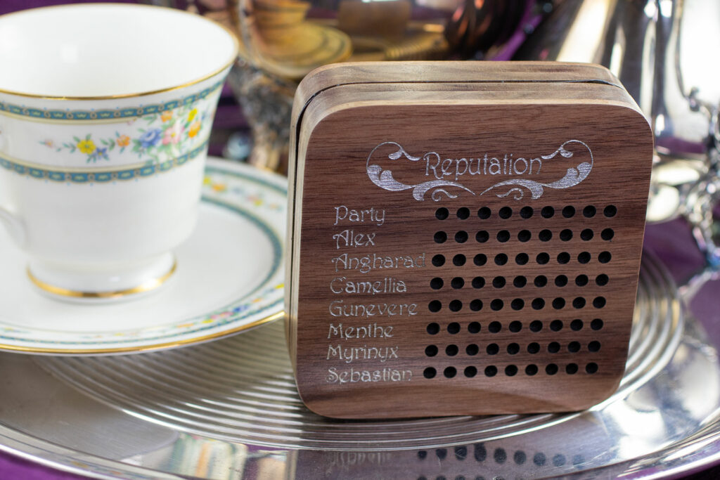 Reputation tracker - a wooden box with a list of names on the face, each with a row of holes that accept cribbage pegs.