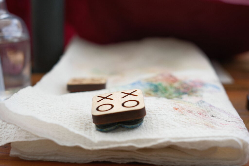 Artistic shot of an XOXO stamp sitting on a wrinkled paper towel stained with ink. Another stamp is visible out-of-focus in the background.