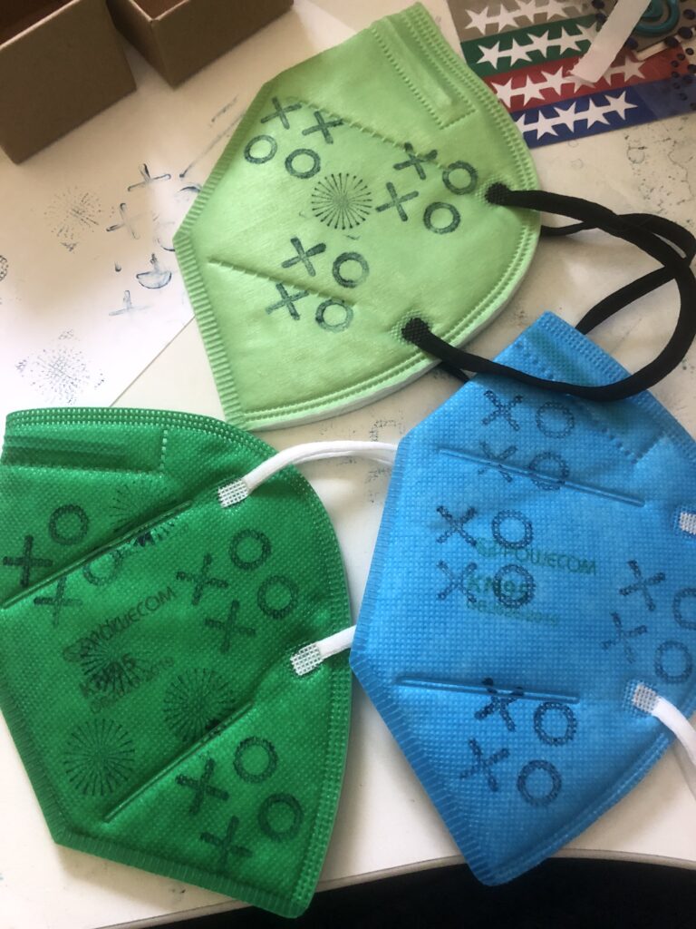 KN95 masks in blue and two shades of green, stamped with XOXO