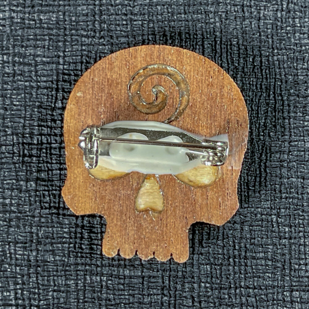 Dark-colored skull pin reverse showing the pin backing.