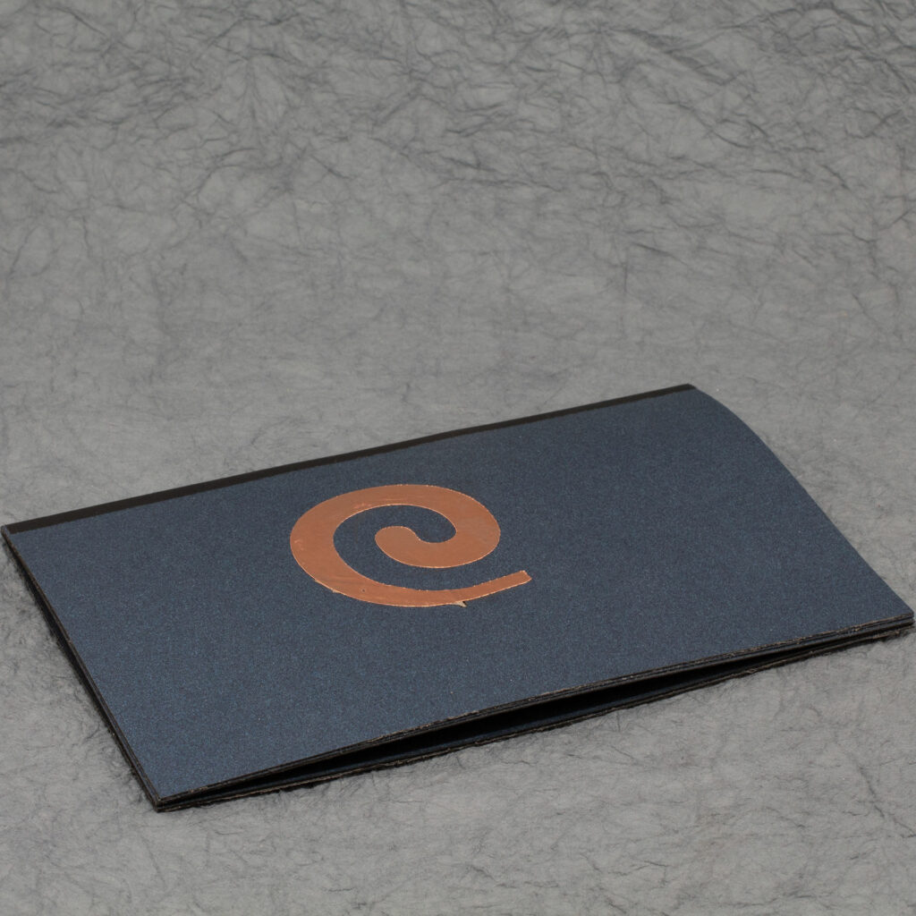 Closed Spiral Crystal pop up card. The side is dark blue with a metallic copper spiral. A strip of black covers the central fold.