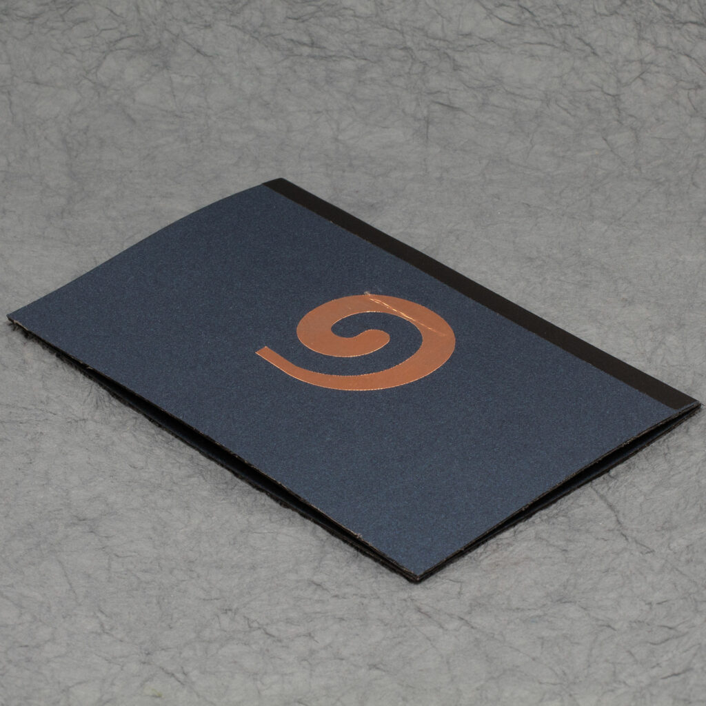 Closed Spiral Crystal pop up card. The side is dark blue with a metallic copper spiral. A ridge is slightly visible under part of the spiral. A strip of black covers the central fold.