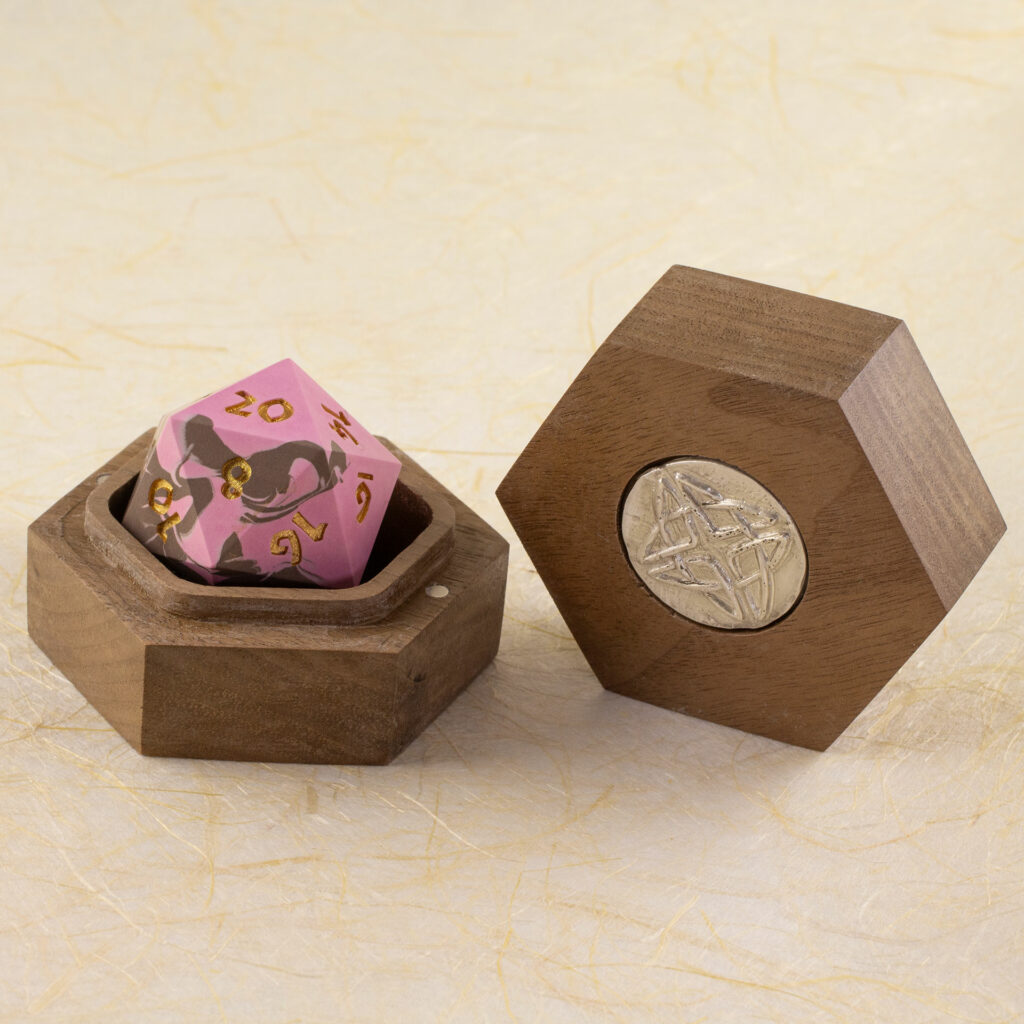 Walnut Hex Chonk Box with a silver Celtic knotwork medallion in the lid, open with a pink and brown 20-sided Jesmonite die inside.