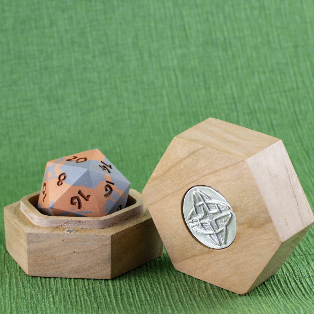 Cherry Hex Chonk Box with a silver Celtic knotwork medallion in the lid, open with a silver and copper 20-sided Jesmonite die inside.