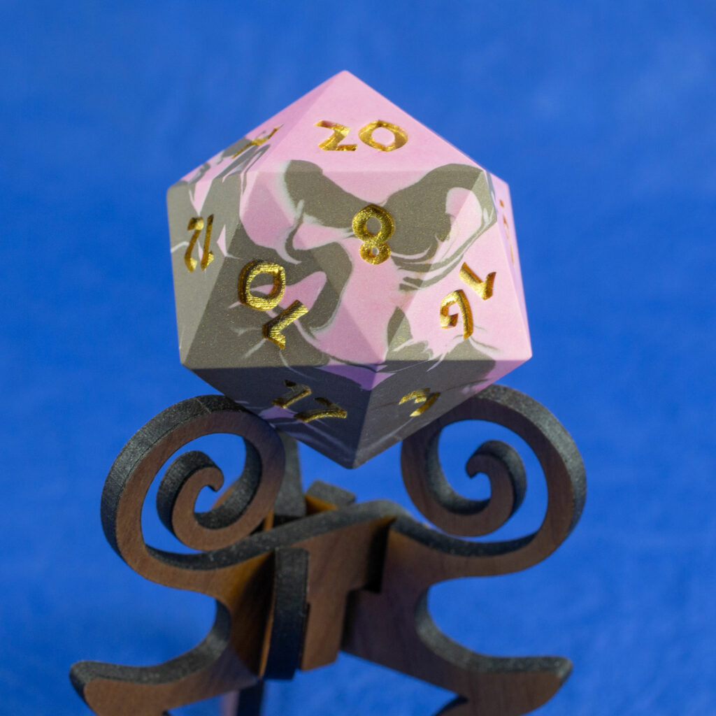 42mm Jesmonite chonk in pink and brown swirled together, the numbers painted in with metallic gold, sitting on a purpleheart stand.