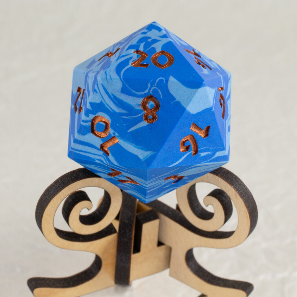 42mm Jesmonite chonk in two shades of blue swirled together, the numbers painted in with metallic copper, sitting on an oak stand.