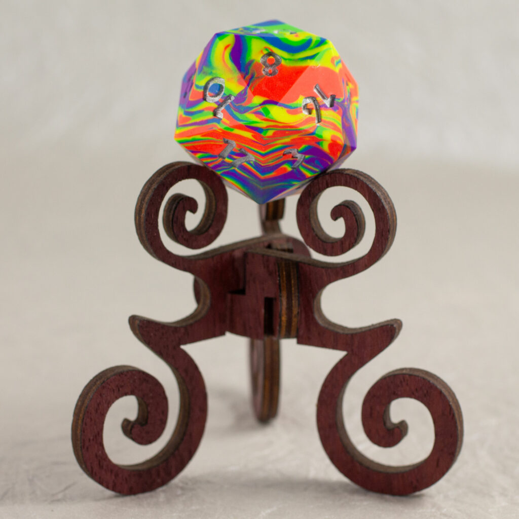 42mm Jesmonite chonk in a rainbow of orange, yellow, green, blue, and purple, swirled together, the numbers painted in with metallic silver, sitting on a purpleheart stand.