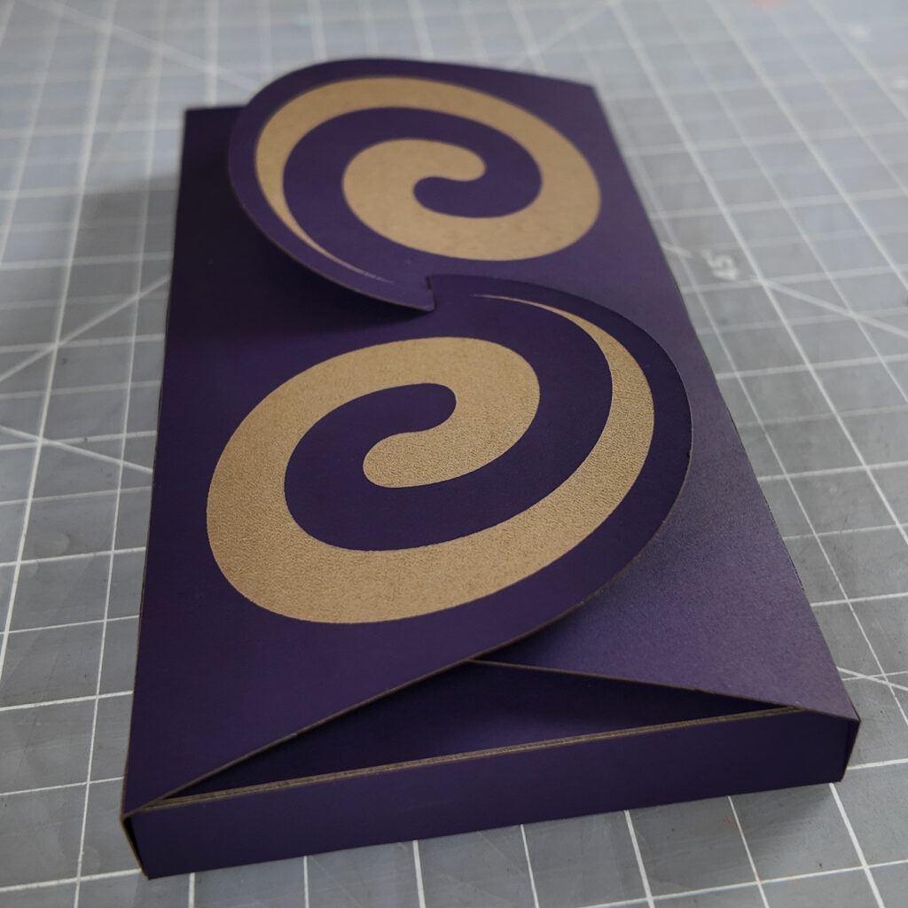 Purple box with a butterfly-style closure with spirals on the flaps.