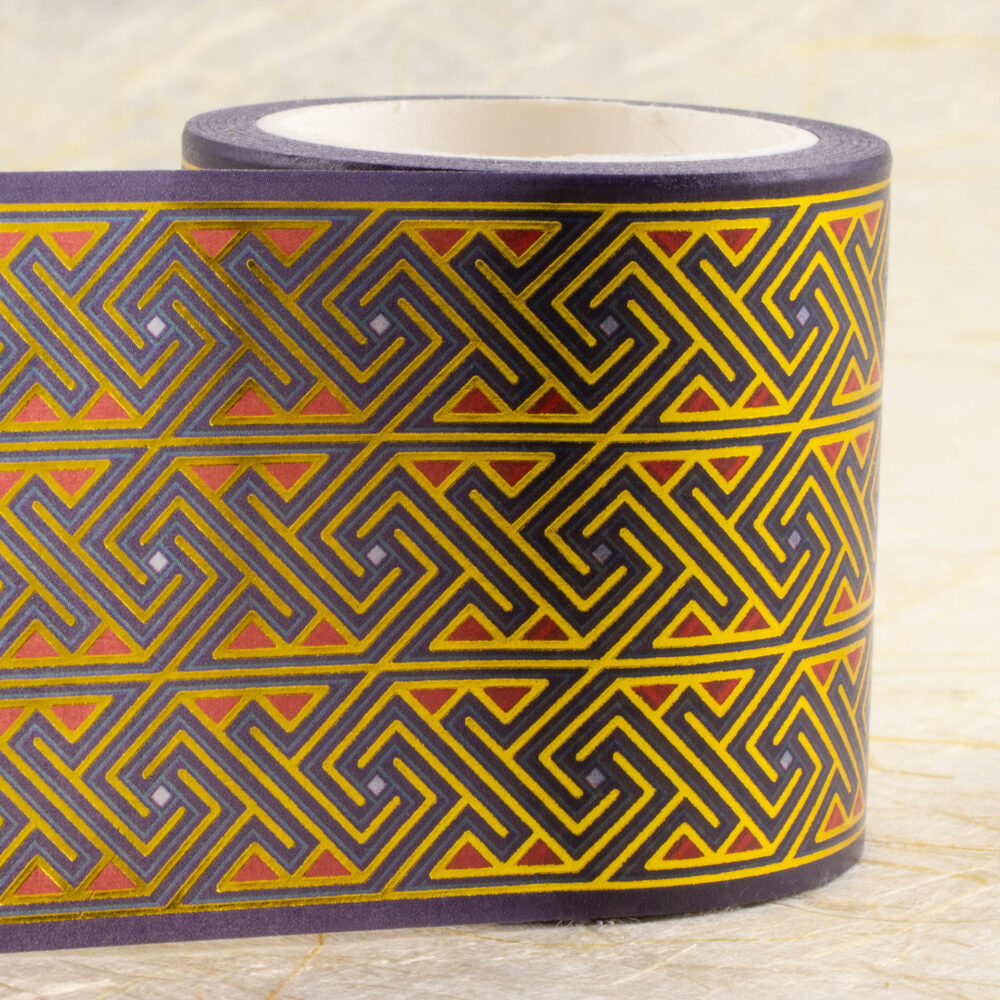 Roll of 45mm-wide washi tape with Celtic key patterns in gold foil on deep purple with red and light blue accents.