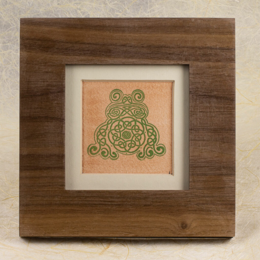 Small Celtic knotwork frog printed in green on a copper square, with a white mat in a walnut frame.