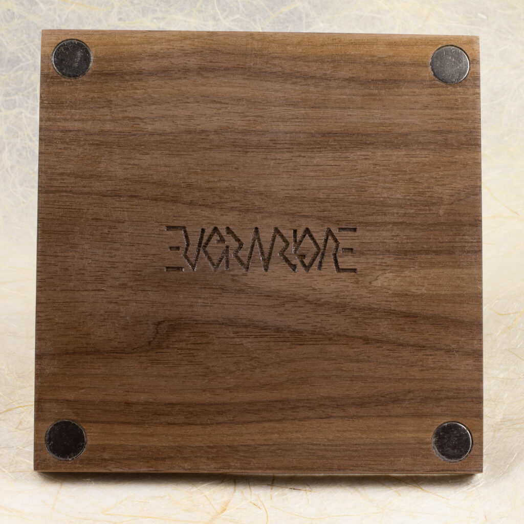 Back side of the 7cm walnut print frame showing the four round magnets in the corners and an engraved Evermore ambigram in the center.