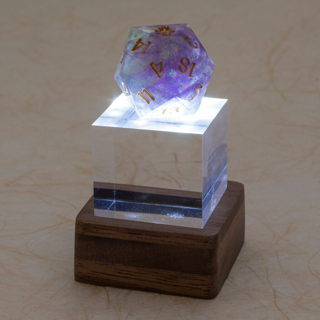 Small light-up stand with a standard 22mm 20-sided resin die in shades of purple with gold numbers.