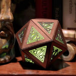 Copper rechargeable icosahedron with yellow light sits on a bookshelf