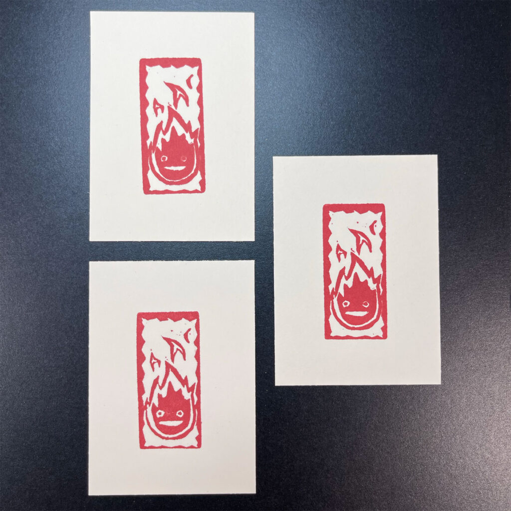Three prints showing how the red ink interacts with different types of paper. Clockwise from top-left and progressively crisper details: the Fabriano Unica paper, Strathmore printmaking paper, and Bristol.